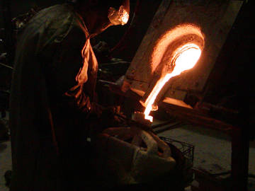 pouring the bronze into the larger shell